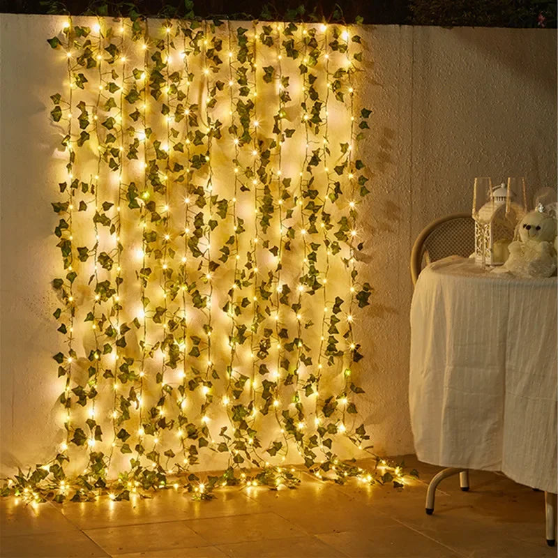 Decorative string lights with green leaves on a wall next to a table with a white tablecloth.
