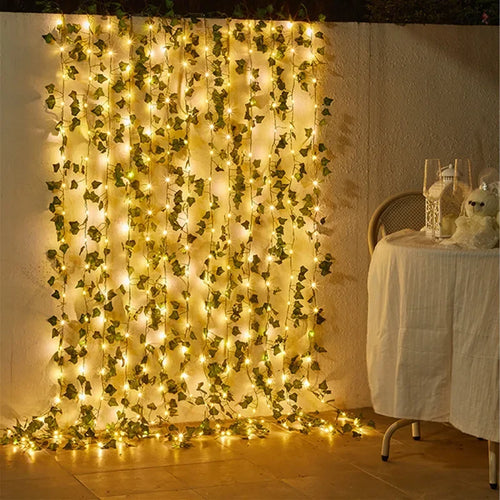 Decorative string lights with green leaves on a wall next to a table with a white tablecloth.