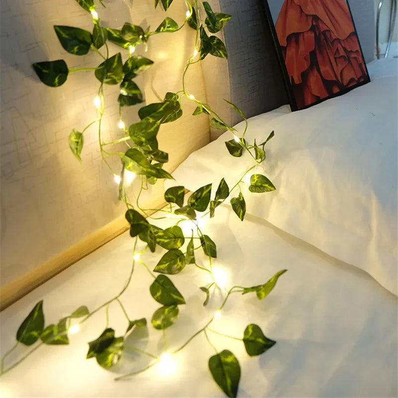 Decorative string lights with green leaves on a white surface